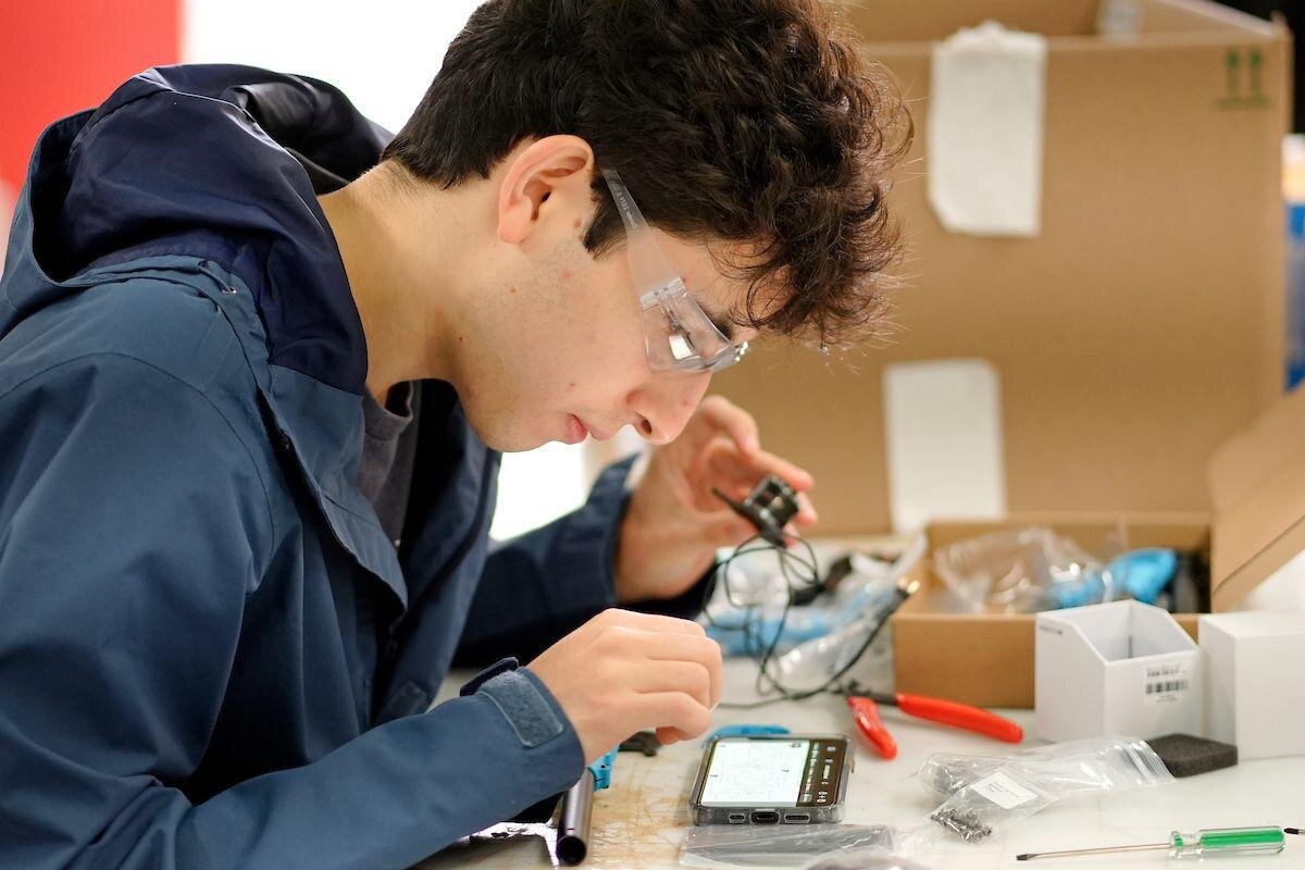 A student soldering a drone flight controller
