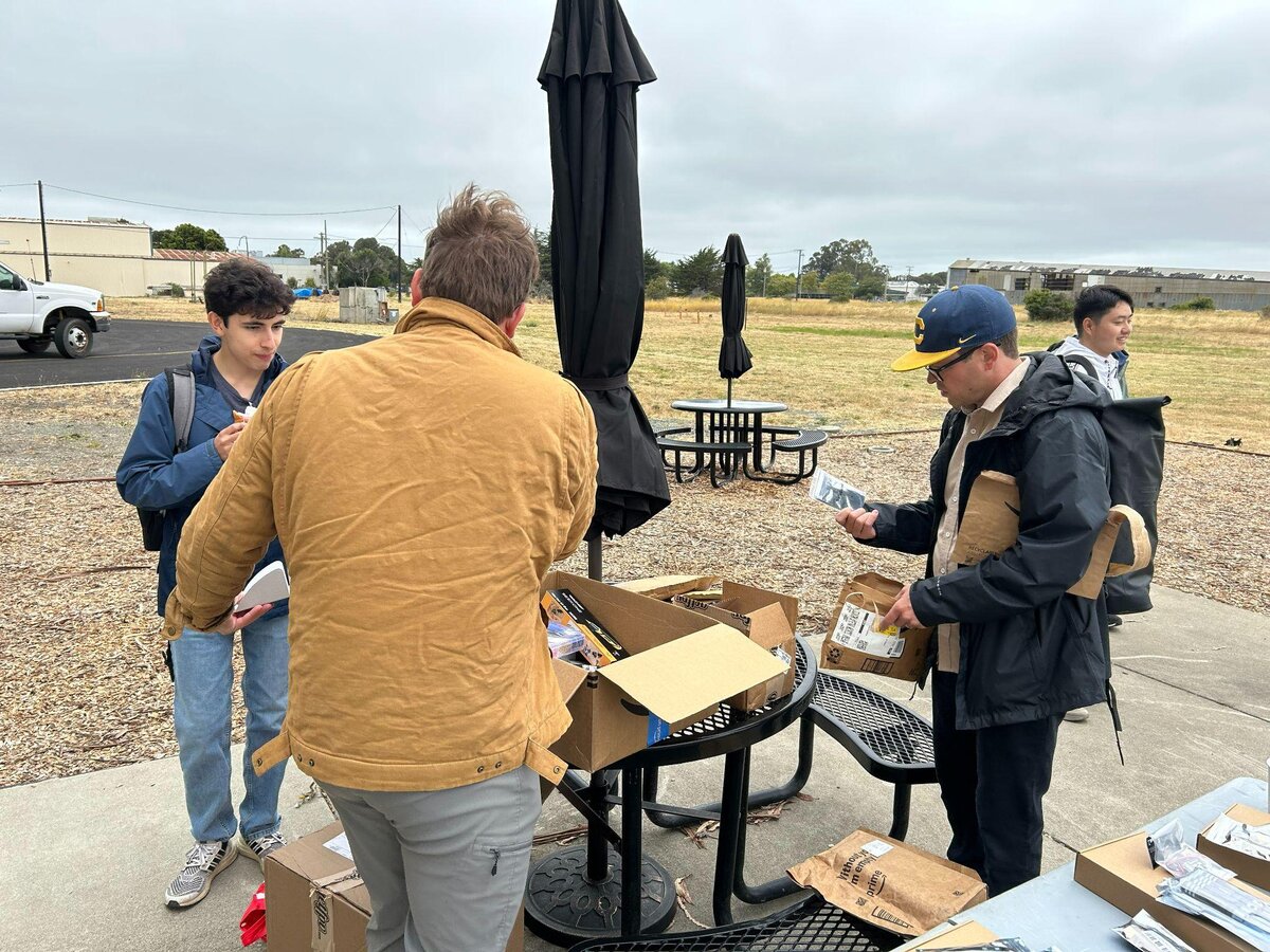 Students unboxing drone kits at an outdoor table at Richmond Field Station